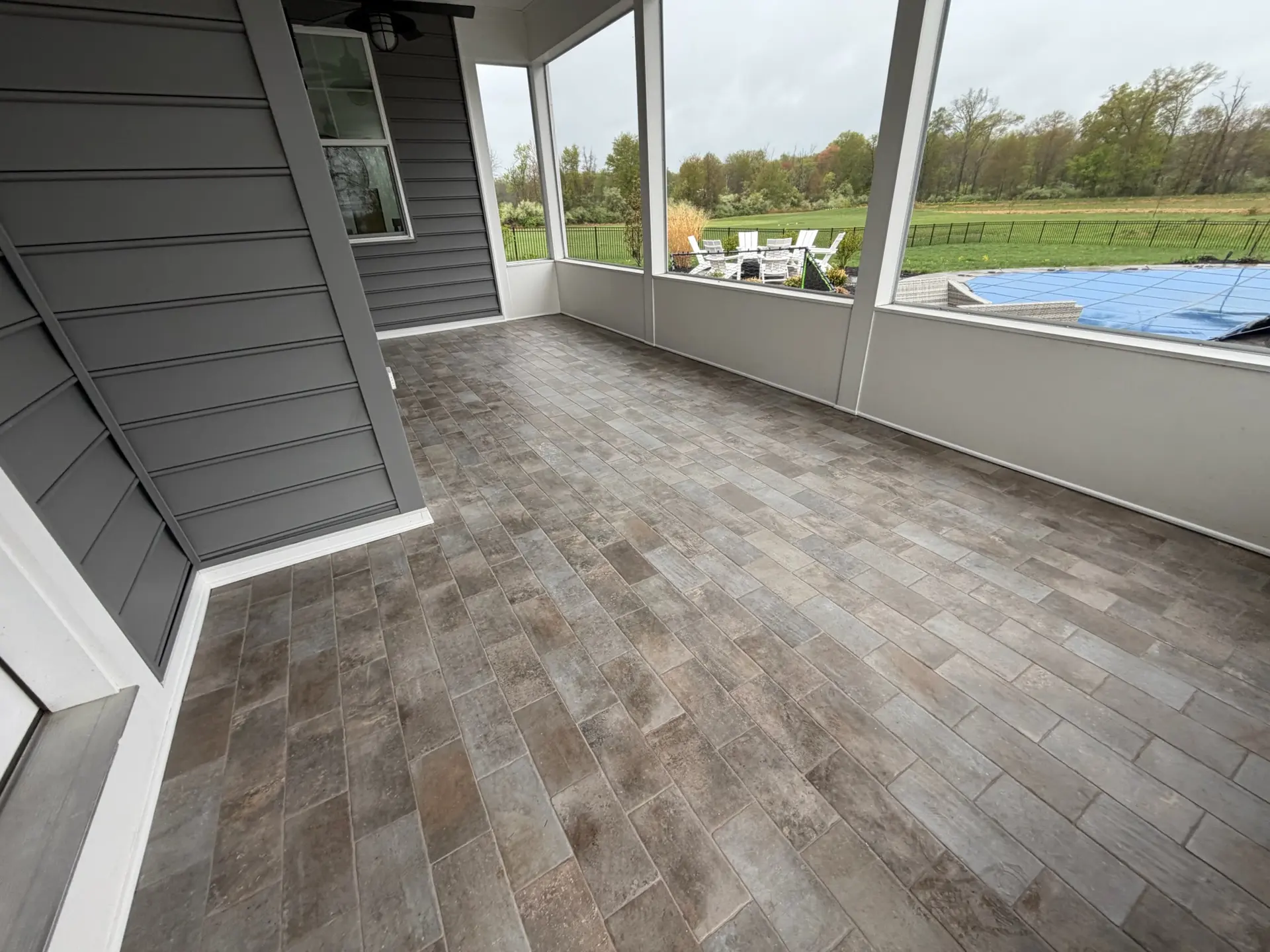Screened porch with large format plank look tile flooring and country views