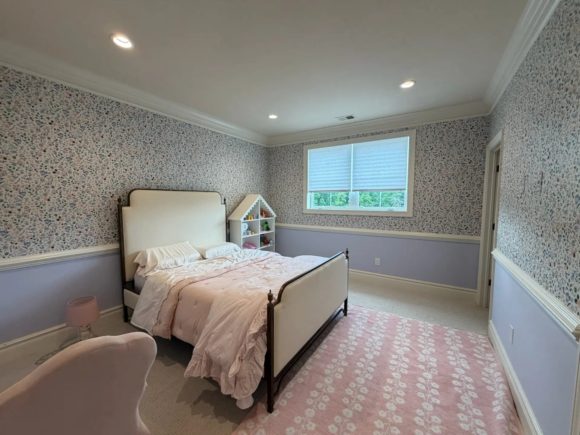 Bedroom with painted lavender wainscoting, patterned wallpaper and crisp white crown molding