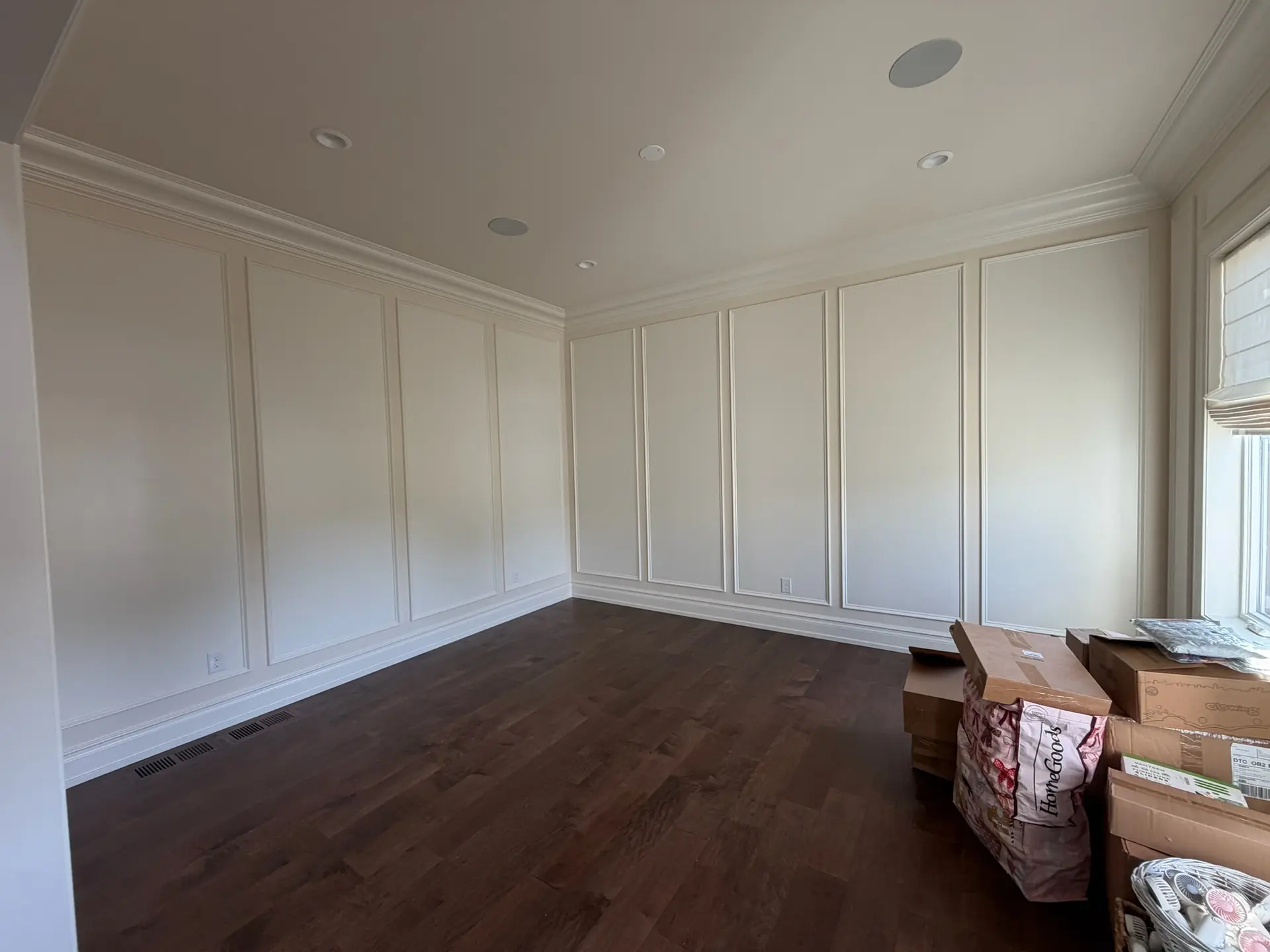 Custom picture frame wall paneling painted white above dark hardwood floors