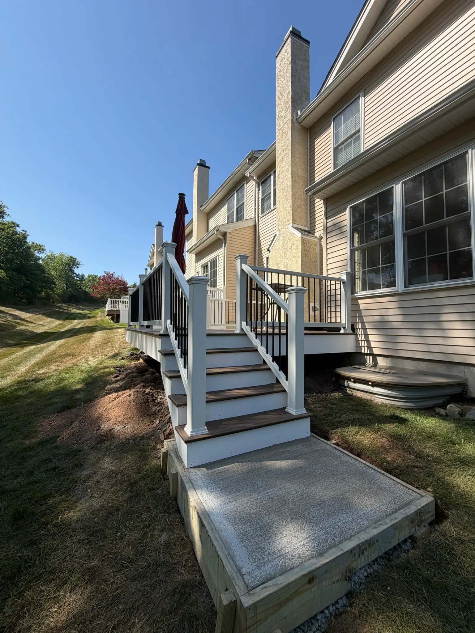 New deck with white railing and stairs leading to a concrete landing