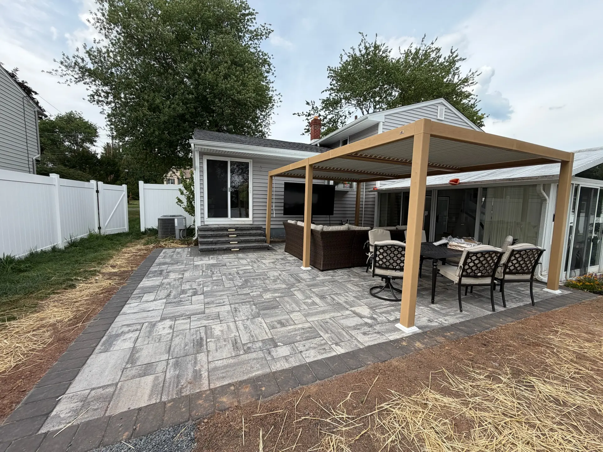 Paver patio with a wooden pergola and outdoor dining and lounge furniture