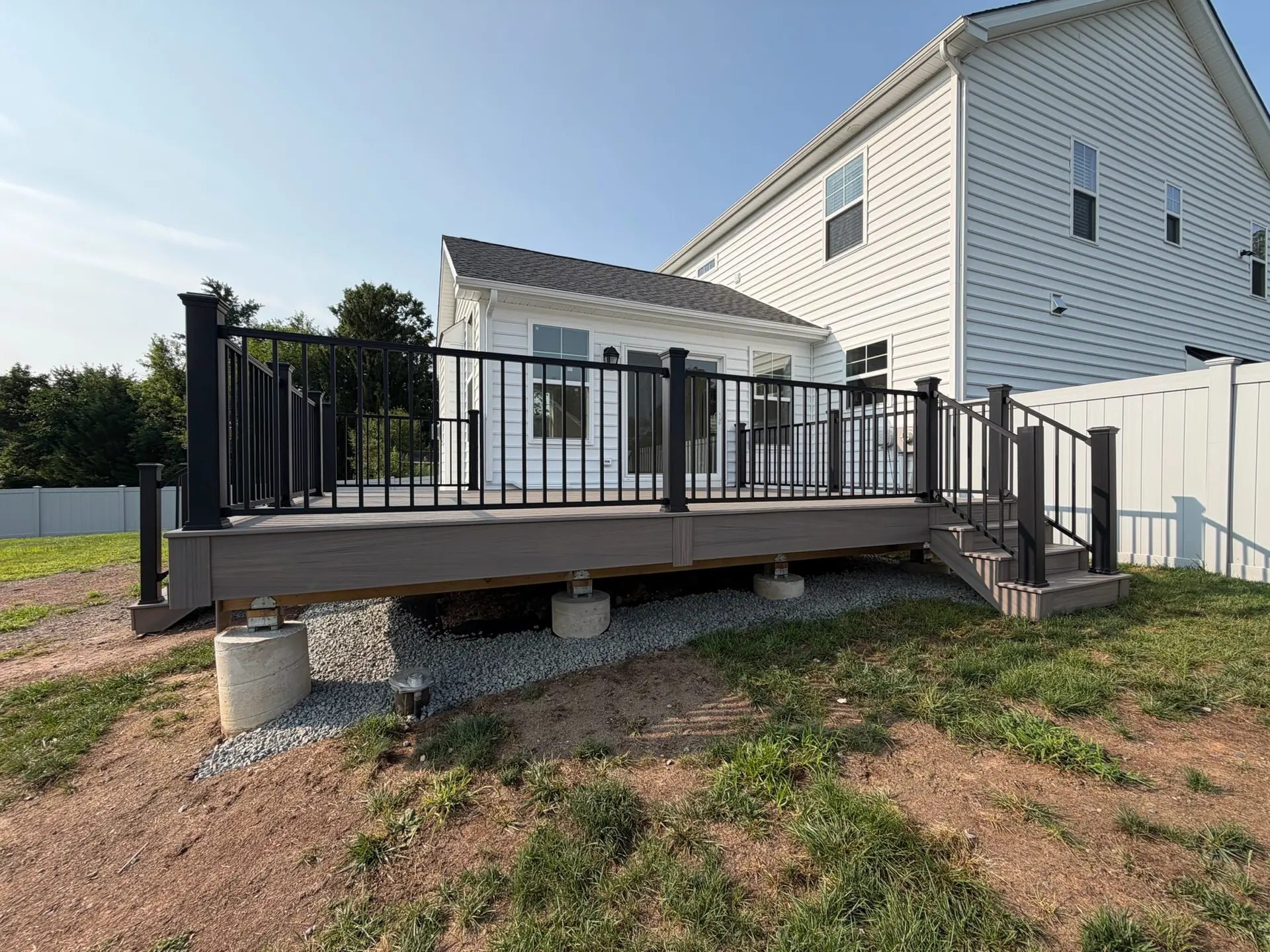 Composite deck with black aluminum railing and stairs on the back of a white home