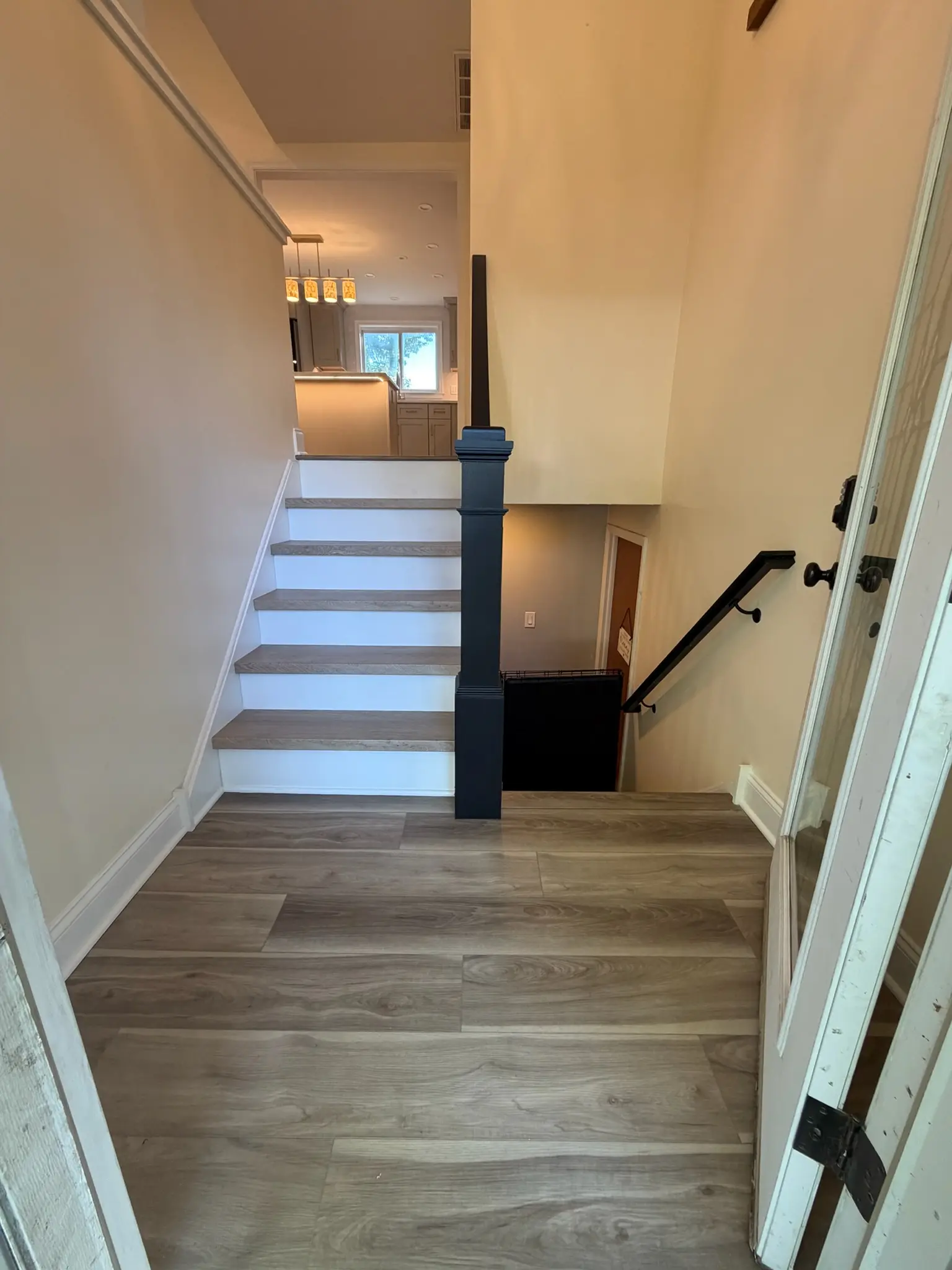 A split level staircase finished with new wood treads, black iron railing and plank flooring