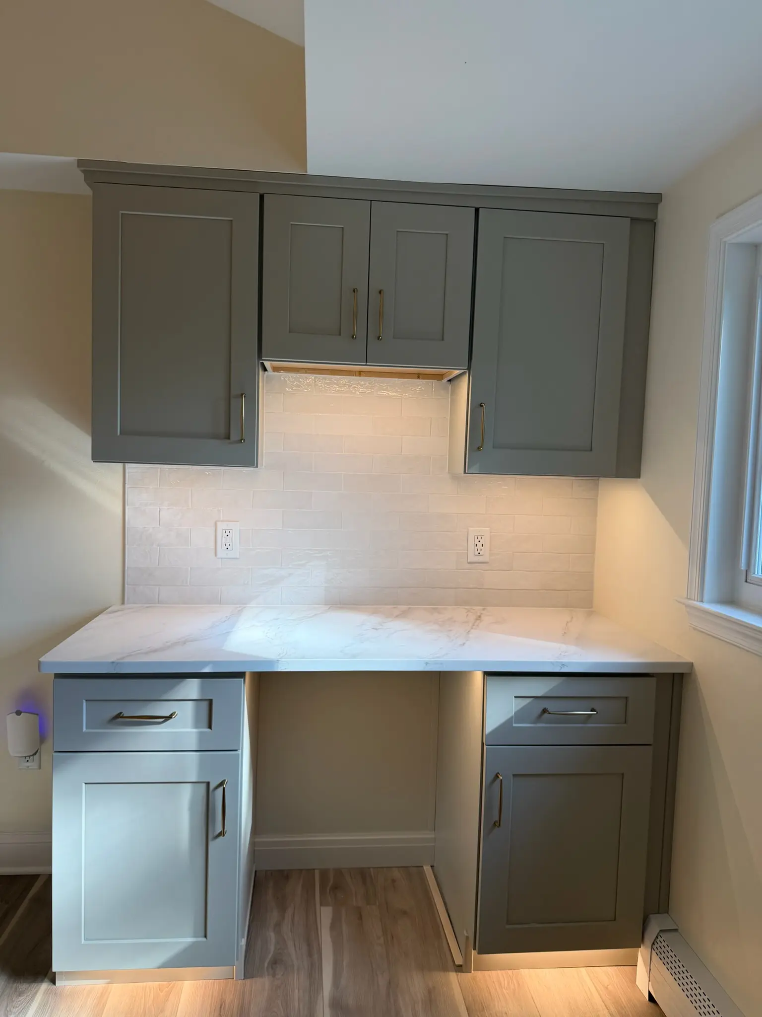 Remodeled kitchen with sage green shaker cabinets, quartz counters and under cabinet lighting
