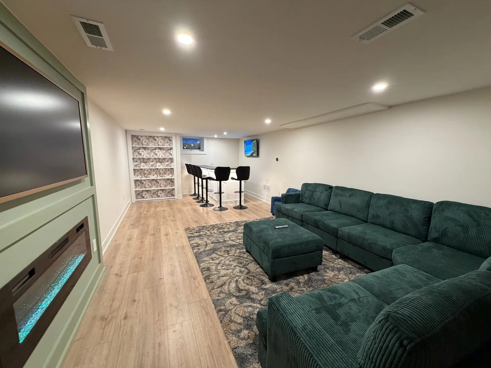 Finished basement lounge with recessed lighting, fireplace feature wall and bar seating